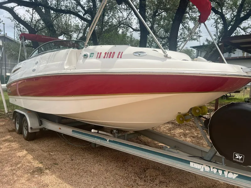 The Image of 2006 Chaparral Sunesta 254 boat on trailer, red and white design, parked outdoors. - 0