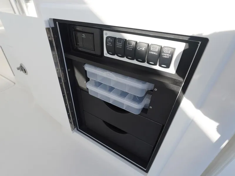 Slide: The Image of 2024 Albemarle 30 Express boat storage compartment with organized tackle boxes and control switches. - 15
