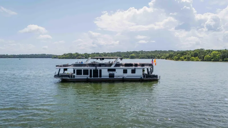 Slide: The Image of 1998 Sumerset houseboat on a serene lake under a partly cloudy sky. - 13
