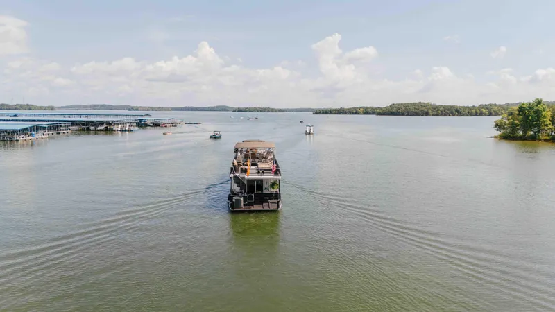 Slide: The Image of 1998 Sumerset houseboat cruising on a serene lake under a clear sky. - 19