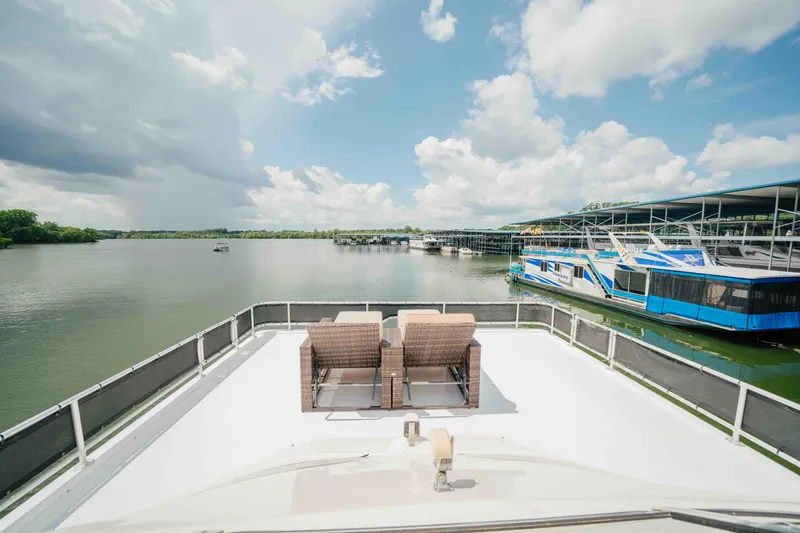 Slide: The Image of 1998 Sumerset houseboat deck with wicker chairs overlooking a serene lake and marina. - 28