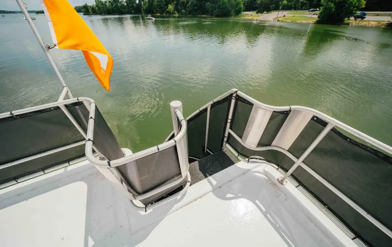Slide: The Image of 1998 Sumerset houseboat deck with orange flag on a calm lake. - 29