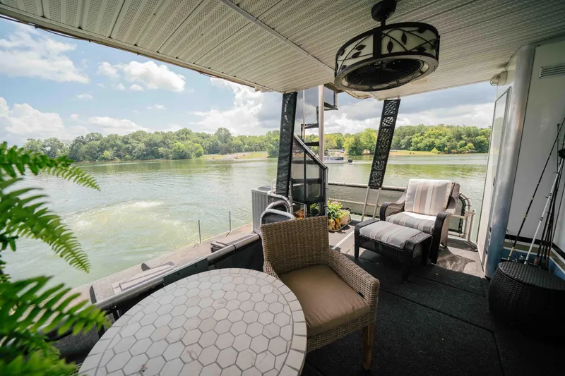 Slide: The Image of 1998 Sumerset houseboat deck with seating, overlooking a serene lake and lush greenery. - 30
