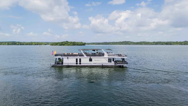 Slide: The Image of 1998 Sumerset houseboat cruising on a lake under a partly cloudy sky. - 5