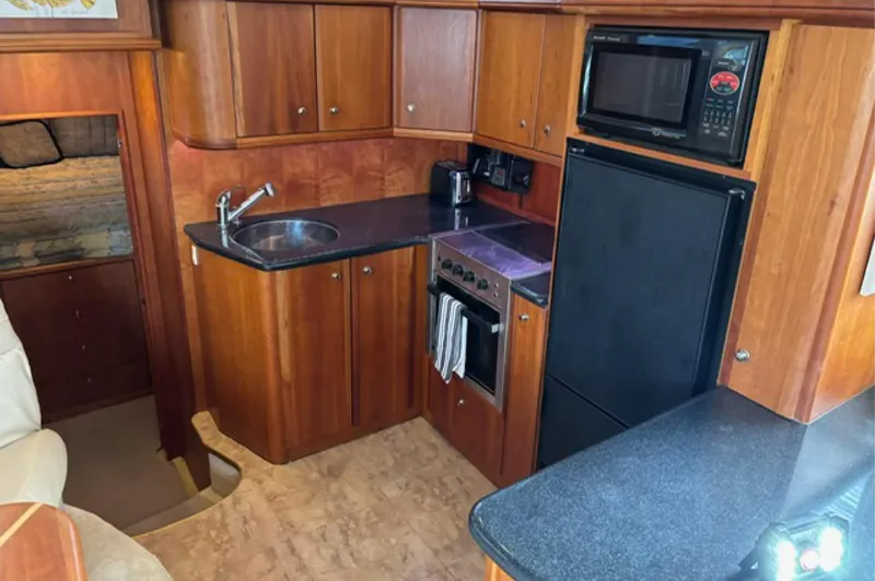 Slide: The Image of 2002 Silverton 43 Motor Yacht kitchen with wood cabinetry, sink, stove, microwave, and refrigerator. - 12