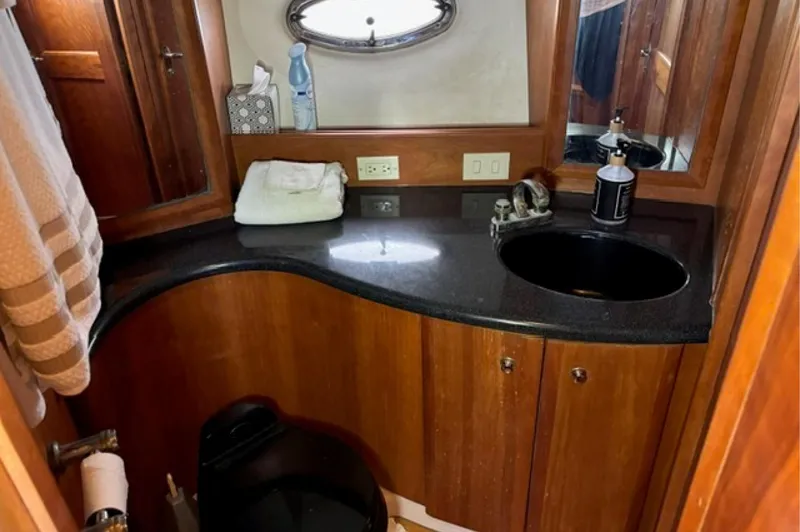 Slide: The Image of Luxurious bathroom in 2002 Silverton 43 Motor Yacht with wood cabinetry and black countertop. - 16
