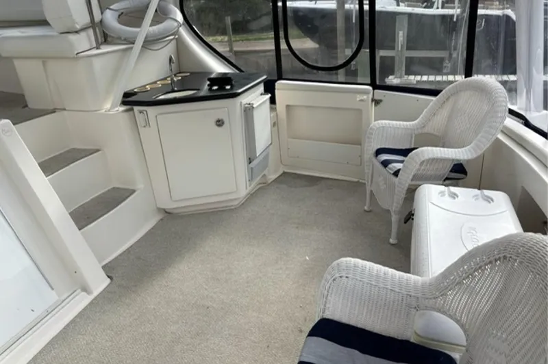 Slide: The Image of 2002 Silverton 43 Motor Yacht interior with wicker chairs and compact kitchenette. - 6