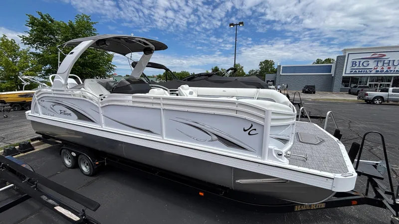 Slide: The Image of 2025 JC Sporttoon 27TT pontoon boat on trailer, parked outdoors under a partly cloudy sky. - 1