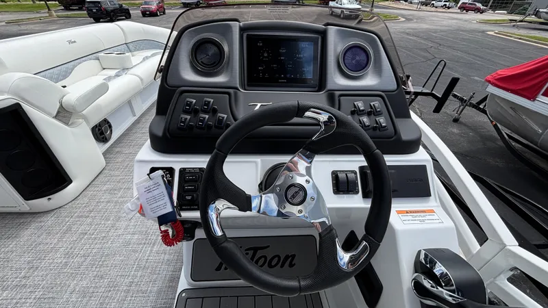 Slide: The Image of 2025 JC Sporttoon 27TT boat dashboard with steering wheel and control panel. - 14