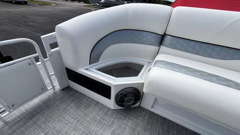 Slide: The Image of 2025 JC Sporttoon 27TT boat interior with white and gray seating, speaker, and storage compartment. - 28