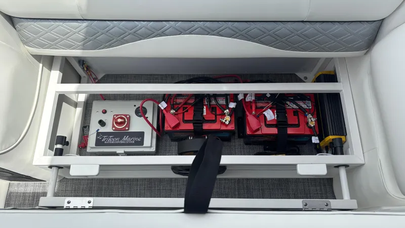 Slide: The Image of 2025 JC Sporttoon 27TT boat battery compartment with red batteries and control panel. - 3