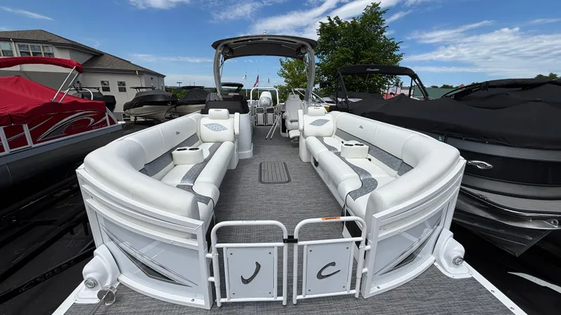 Slide: The Image of 2025 JC Sporttoon 27TT pontoon boat with white seating, docked under a clear blue sky. - 31