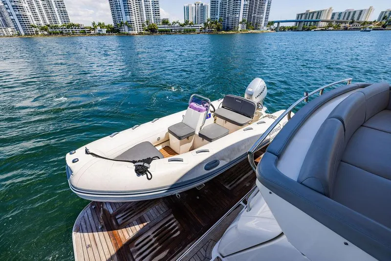 Slide: The Image of 2016 Sea Ray L650 Fly yacht with tender on water, city skyline in background. - 11
