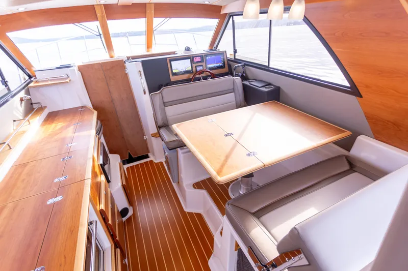 Slide: The Image of 2021 Cutwater C-32 CB interior with wood accents, dining area, and navigation equipment. - 13