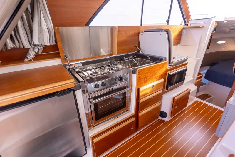 Slide: The Image of 2021 Cutwater C-32 CB yacht kitchen with wood cabinetry, stainless steel appliances, and modern design. - 22