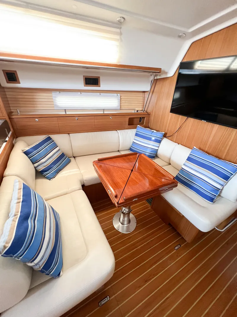 Slide: The Image of 2019 Catalina 425 yacht interior with cozy seating, striped cushions, and wooden table. - 28