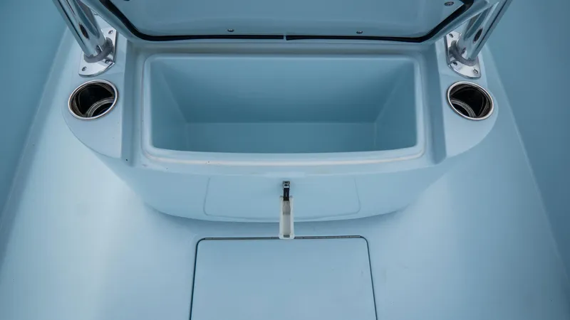 Slide: The Image of 2024 Contender 24 Sport boat storage compartment with cup holders, open lid view. - 15