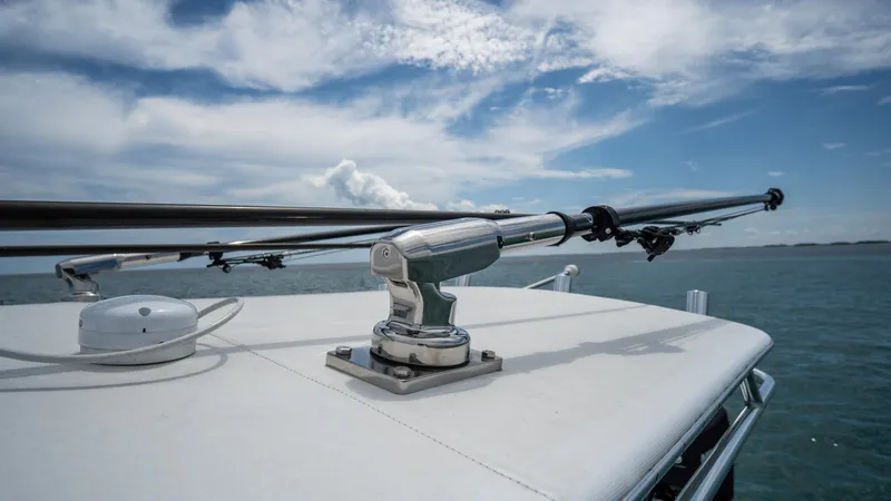 Slide: The Image of 2024 Contender 24 Sport boat with fishing rod holder on deck, under a partly cloudy sky. - 34