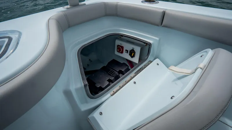 Slide: The Image of 2024 Contender 24 Sport boat storage compartment with battery access and control switches. - 37