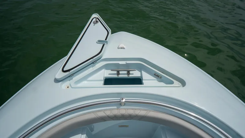 Slide: The Image of 2024 Contender 24 Sport boat bow with open hatch on calm water. - 7