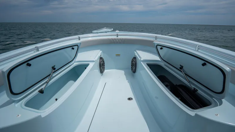 Slide: The Image of 2024 Contender 24 Sport boat with open storage compartments on a calm sea. - 9