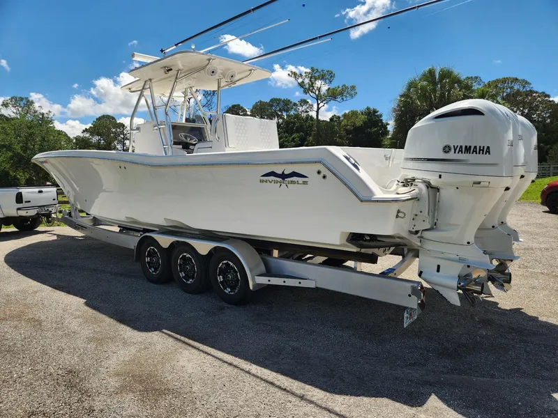 Slide: The Image of 2013 Invincible 36 Open Fisherman boat on trailer with Yamaha engines, parked outdoors. - 2