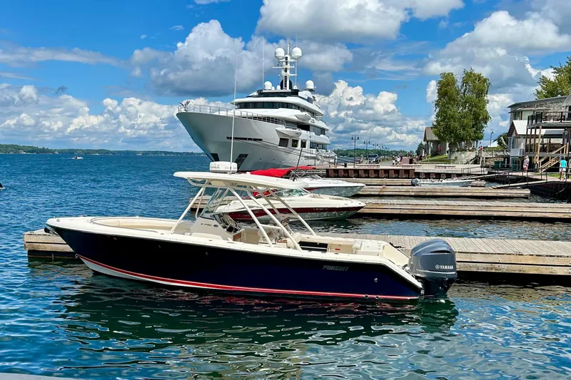 Slide: The Image of 2012 Pursuit S 280 Sport boat docked in a marina, clear skies, luxury yacht in background. - 1