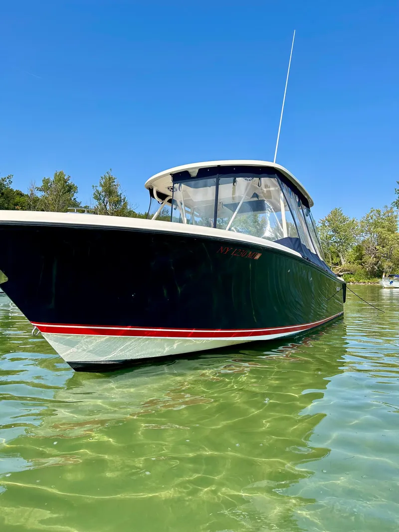 Slide: The Image of 2012 Pursuit S 280 Sport boat on clear water, sunny day, trees in background. - 2