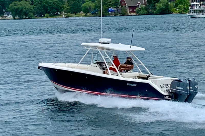Slide: The Image of 2012 Pursuit S 280 Sport boat cruising on a lake with lush green shoreline. - 5