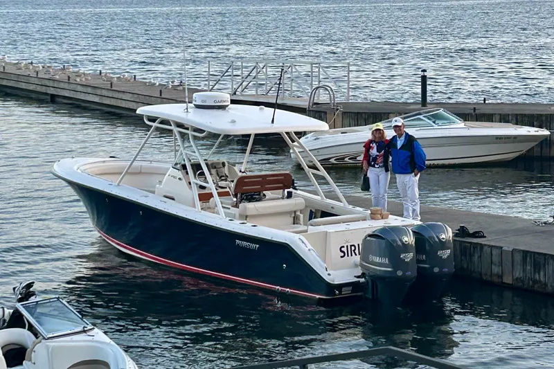 Slide: The Image of 2012 Pursuit S 280 Sport boat docked with two people standing nearby. - 6