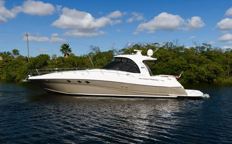 The Image of 2006 Sea Ray 52 Sundancer yacht cruising on a sunny day, surrounded by lush greenery. - 0