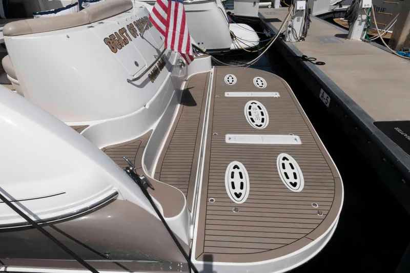 Slide: The Image of 2006 Sea Ray 52 Sundancer yacht docked, featuring a spacious swim platform and American flag. - 16