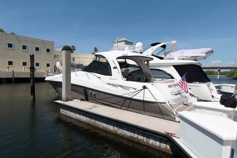 Slide: The Image of 2006 Sea Ray 52 Sundancer yacht docked at marina, clear sky, American flag displayed. - 4