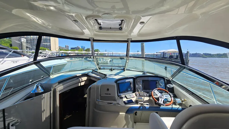 Slide: The Image of 2005 Sea Ray 390 Sundancer cockpit with modern navigation equipment, docked by a city waterfront. - 12