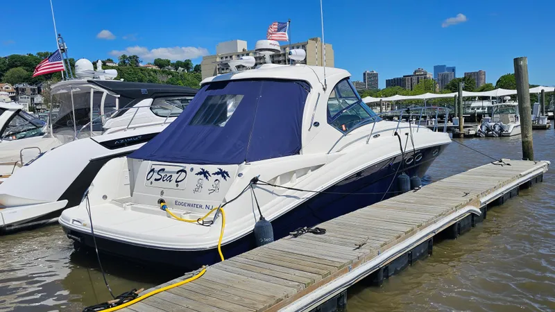 Slide: The Image of 2005 Sea Ray 390 Sundancer docked at marina, clear sky, city skyline in background. - 2