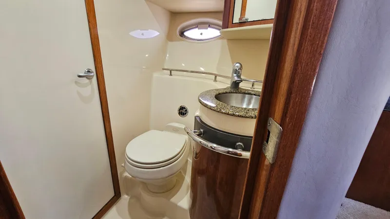 Slide: The Image of 2005 Sea Ray 390 Sundancer bathroom with toilet, sink, and wooden cabinetry. - 36
