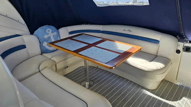 Slide: The Image of Interior of 2005 Sea Ray 390 Sundancer with cushioned seating and wooden table. - 6