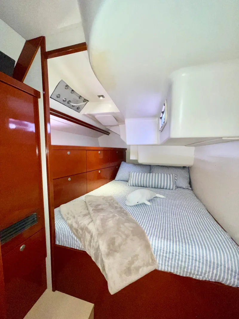Slide: The Image of Cozy cabin interior of 2006 Hanse 461 yacht with striped bedding and wooden cabinetry. - 25