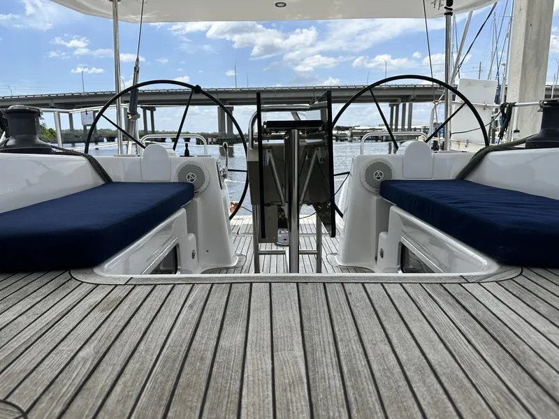 Slide: The Image of 2006 Hanse 461 yacht deck with dual steering wheels and blue seating, docked near a bridge. - 27