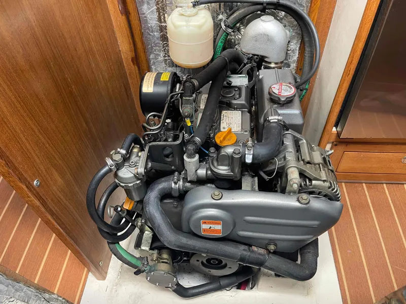 Slide: The Image of 2006 Hunter 309 engine in a wooden compartment, showcasing mechanical components and hoses. - 19