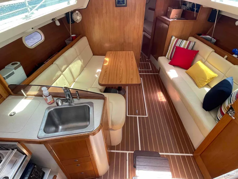 Slide: The Image of Interior of a 2006 Hunter 309 sailboat with cozy seating and a compact kitchen area. - 23