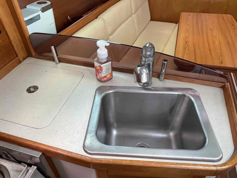 Slide: The Image of 2006 Hunter 309 yacht kitchen with sink, countertop, and seating area. - 28