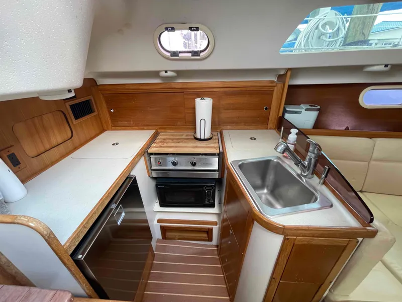 Slide: The Image of Compact kitchen in a 2006 Hunter 309 sailboat with stove, sink, and wood accents. - 3