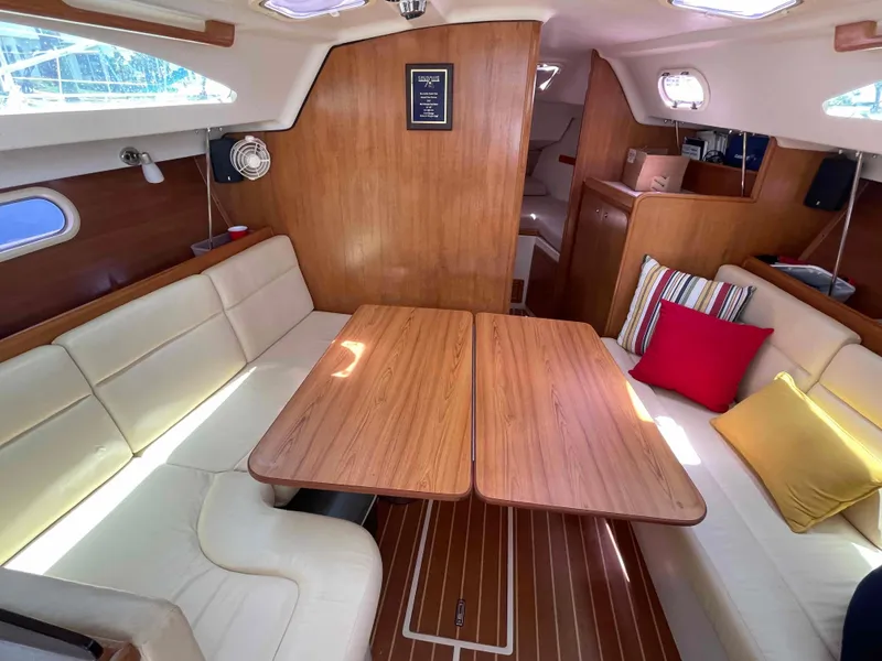 Slide: The Image of 2006 Hunter 309 yacht interior with wooden table, cream seating, and colorful cushions. - 31