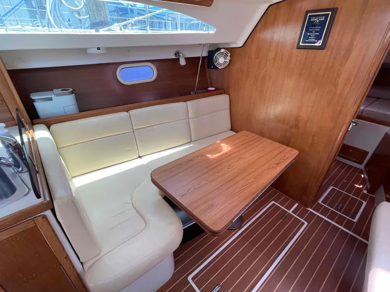 Slide: The Image of 2006 Hunter 309 yacht interior with wooden table, cream seating, and sleek design. - 33