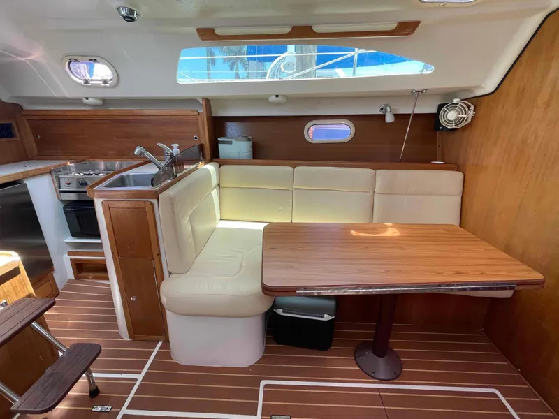 Slide: The Image of Interior of a 2006 Hunter 309 sailboat with wooden dining area and kitchenette. - 4