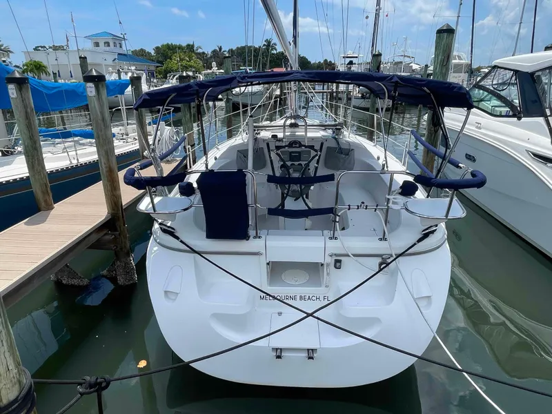 Slide: The Image of 2006 Hunter 309 sailboat docked at marina, featuring spacious cockpit and blue canopy. - 42