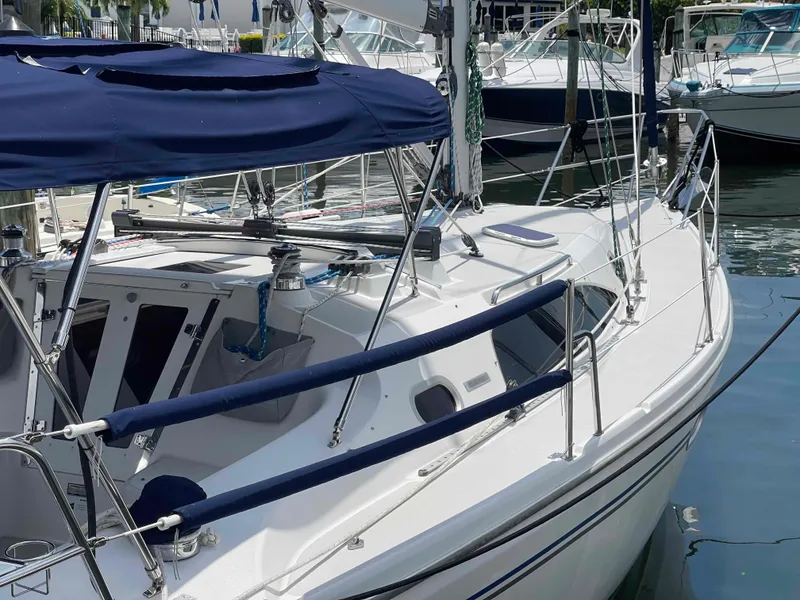 Slide: The Image of 2006 Hunter 309 sailboat docked, featuring blue canopy and sleek white design. - 43