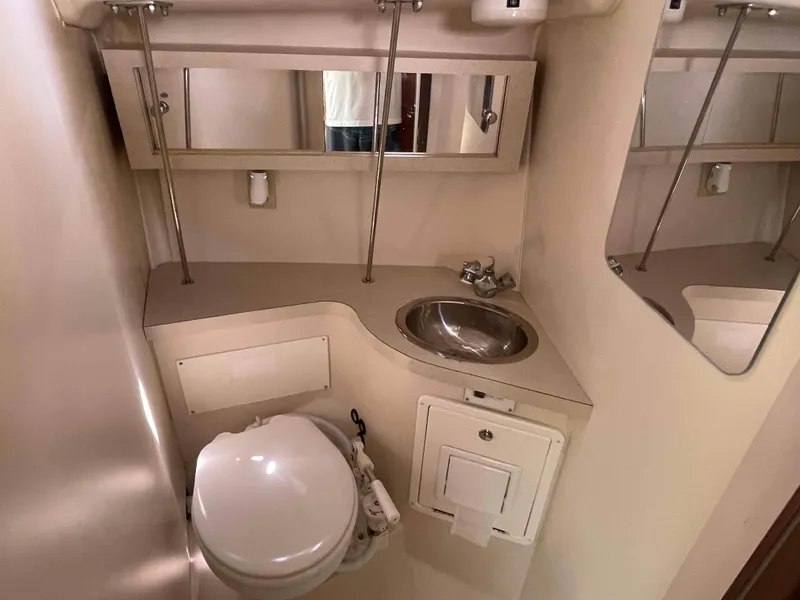 Slide: The Image of Compact bathroom in a 2006 Hunter 309 boat, featuring a toilet, sink, and mirror. - 7