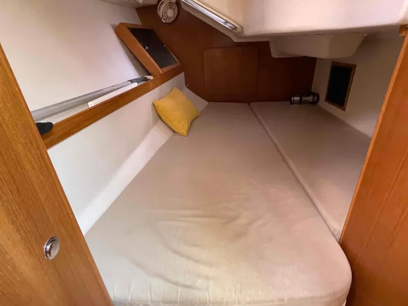 Slide: The Image of Cozy cabin interior of 2006 Hunter 309 sailboat with cushioned bed and wooden accents. - 8
